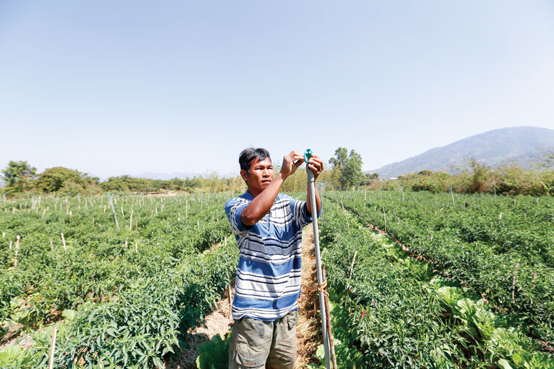 Anh Rơ Jê Ha Mi chỉnh sửa bép nước để tưới cho vườn ớt, bắp sú