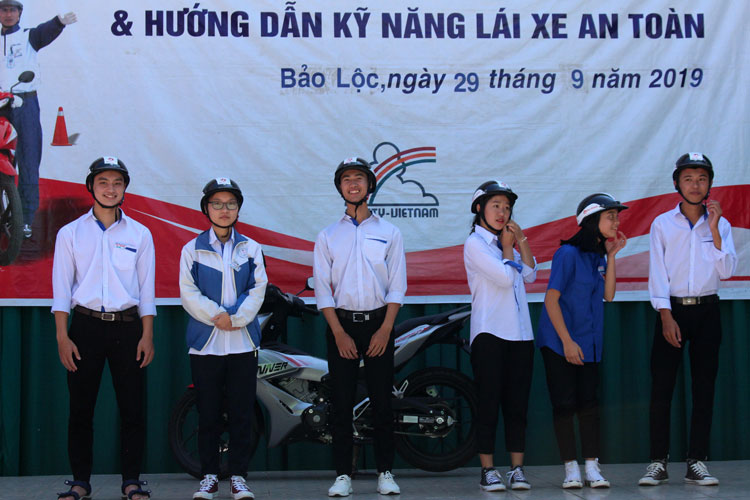 Nhân viên Công ty TNHH Honda Bảo Khánh hướng dẫn học sinh cách đội mũ bảo hiểm đúng quy định