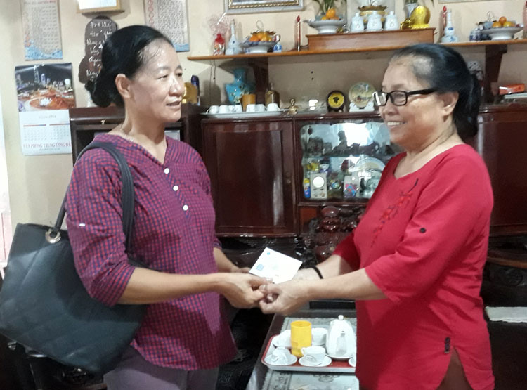 Bà Nguyễn Thị Hơn (bìa trái) - cán bộ đại lý BHYT thị trấn Đạ Tẻh đến tận nhà trao thẻ y tế tự nguyện trong niềm vui của người dân. Ảnh: N.T.T