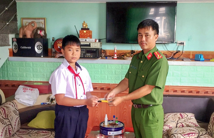 Em Cao Chí Nguyên (học sinh lớp 6A10, Trường THCS Hùng Vương, TP Bảo Lộc) bàn giao số tiền nhặt được cho Công an Phường 1 nhờ tìm trả lại người đánh rơi