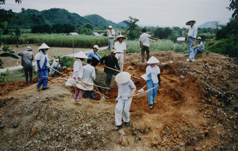 Tiến sĩ Đào Lin Côn đang chỉ đạo khai quật tại Gò Ông Định (người mặc bộ đồ trắng, đội nón lá đứng giữa gần nhóm khiêng đất). Ảnh tư liệu Bảo tàng Lâm Đồng