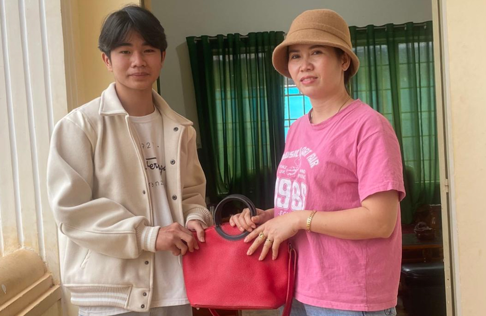 Em Nguyễn Tuấn Anh trao lại túi xách cho chị Tạ Thị Lương tại trụ sở Công an Gia Lâm. Ảnh: Công an Gia Lâm