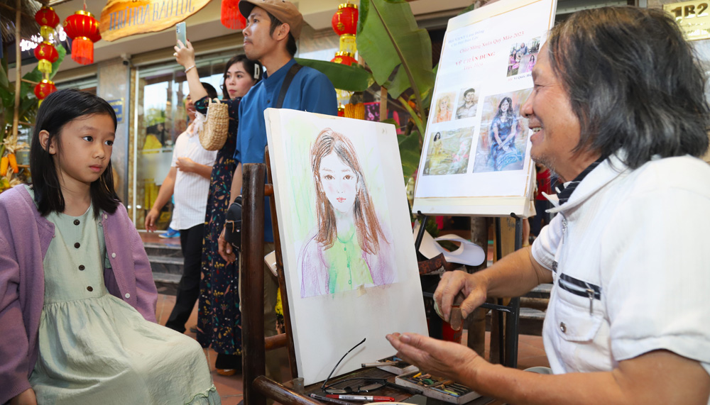 Họa sĩ Vi Quốc Hiệp vẽ tranh chân dung tặng người dân đến tham quan, thưởng lãm tại Phố Ông đồ