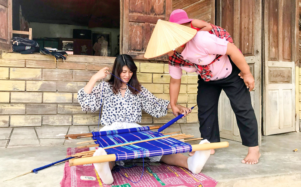 Nghệ nhân dân gian dệt thổ cẩm ở thôn Đam Pao hướng dẫn du khách thực hành các công đoạn dệt