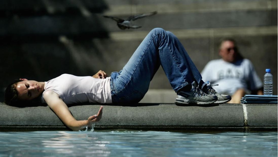 Một phụ nữ tránh nóng tại một đài phun nước trên Quảng trường Trafalgar, London, Anh, vào tháng 7/2003