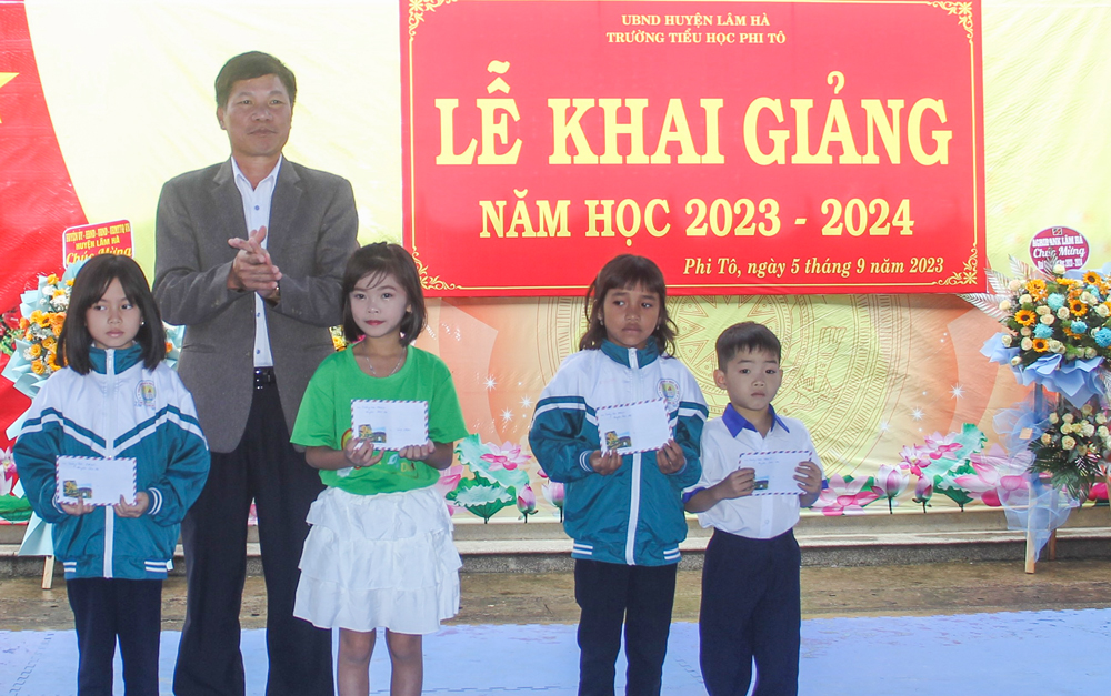 Đồng chí Nguyễn Văn Tân - Chủ tịch HĐND huyện Lâm Hà trao quà cho học sinh