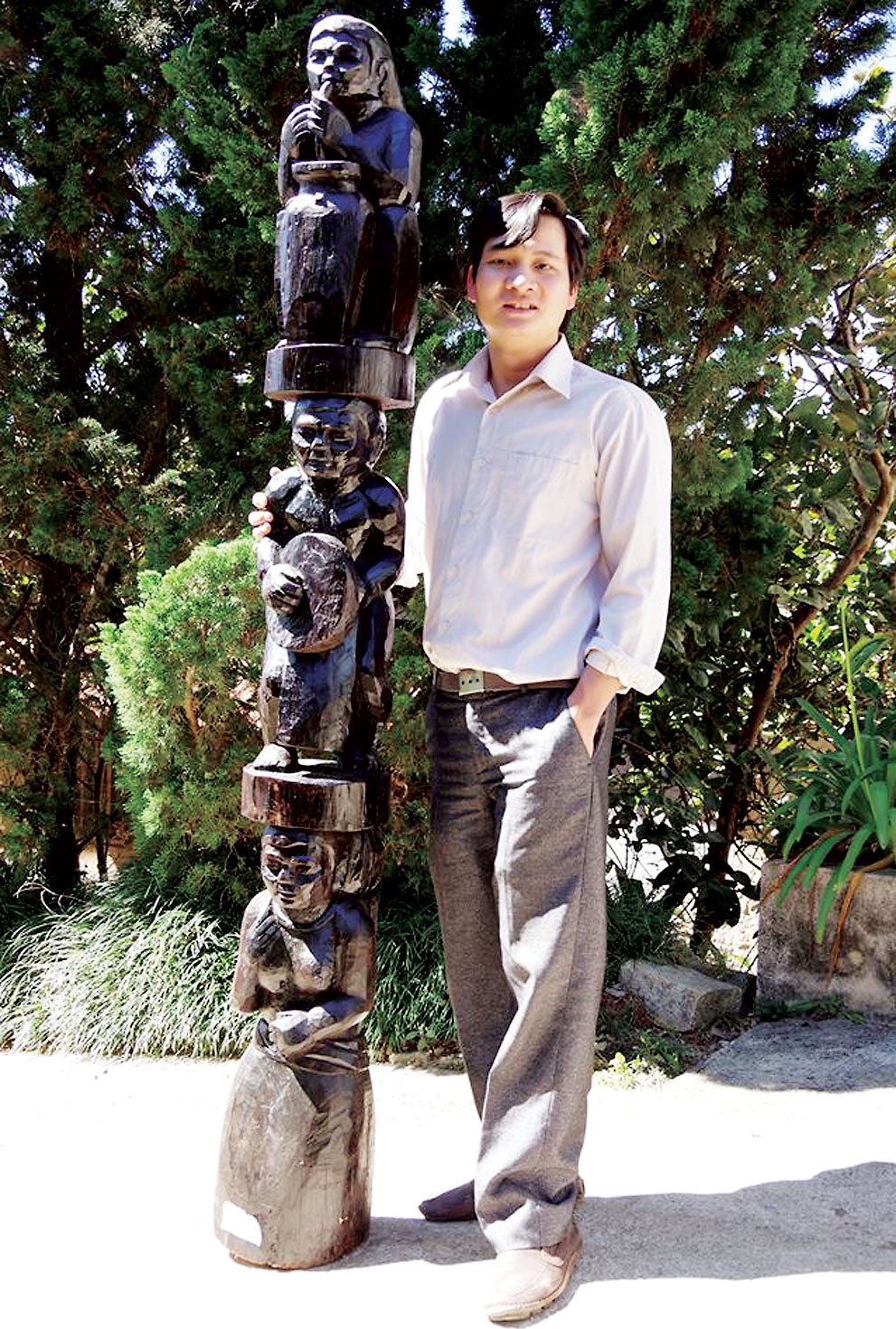 Tác giả Đỗ Xuân Phòng cùng tác phẩm điêu khắc gỗ “Văn hóa Tây Nguyên”