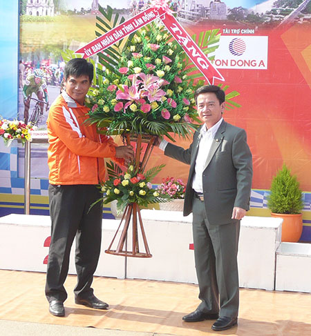Ông Phan Văn Đa, Phó Chủ tịch UBND tỉnh Lâm Đồng trao lẵng hoa cho Ban tổ chức chào mừng đoàn đua đến Lâm Đồng