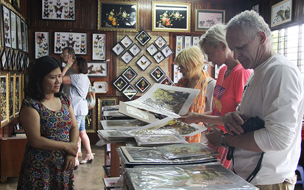 Chị Vũ Thị Nguyệt Ánh (bìa trái) giới thiệu tranh cho du khách