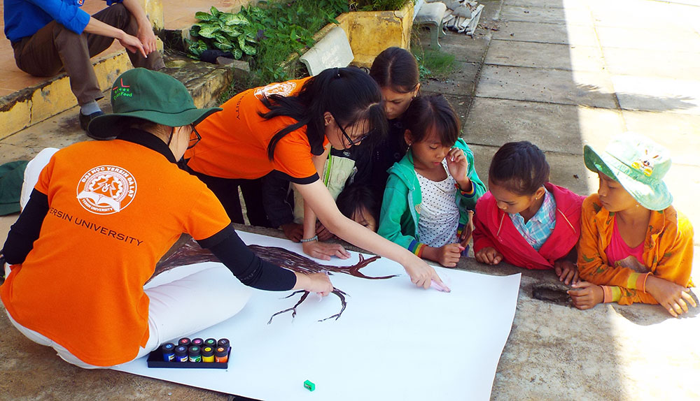 SV ĐH Yersin vẽ pano hình cây xanh, tổ chức để các em in dấu vân tay nhằm tuyên truyền bảo vệ rừng và môi trường sống (Ảnh chụp tại Tà Hine - Đức Trọng)