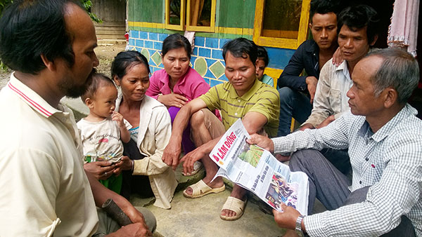 Già làng Kră Jăn Ha Xuyên đang trao đổi thông tin trên báo chí với người dân trong thôn