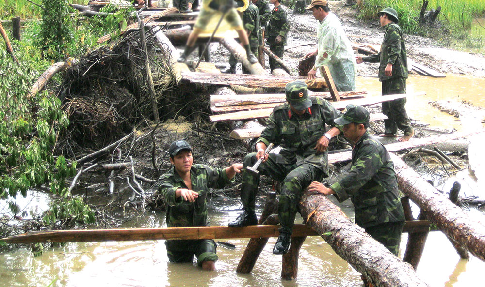Cán bộ, chiến sỹ lực lượng vũ trang tỉnh giúp dân làm cầu vượt lũ ở Đam Rông. Ảnh: XUÂN NGỌC