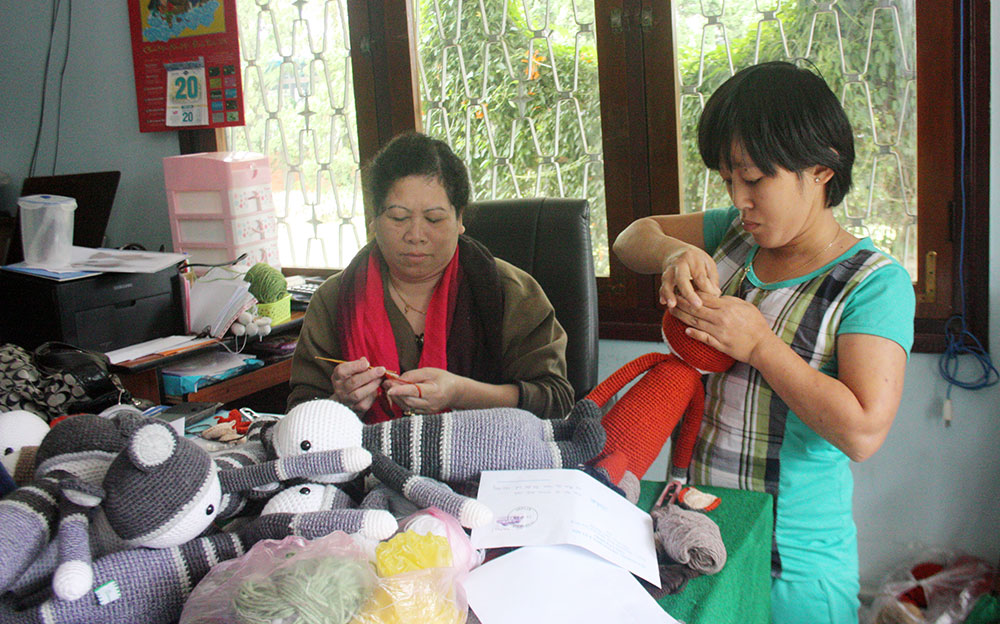 Chị Vũ Thị Kim Hòa (bên trái) cùng với xã viên đang sản xuất bộ thú nhồi bông đan móc tay. Ảnh: Y.Thy