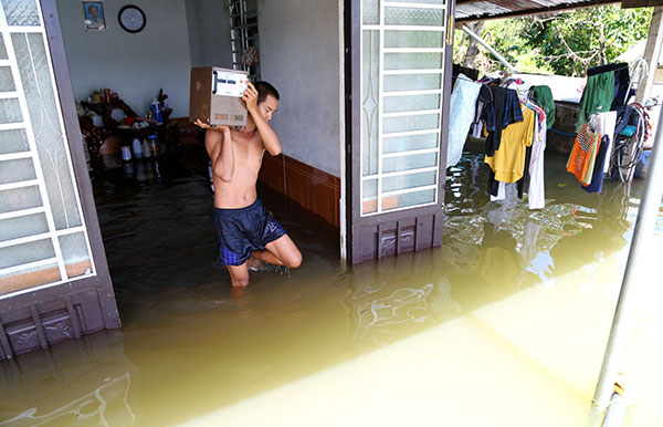 Nước ngập vào trong nhà khoảng 30 cm, Trần Mạnh Linh (29 tuổi, thôn Hà Lâm) di chuyển một số vật dụng ra khỏi nhà vì sợ nước tiếp tục dâng cao. Ảnh: C.Thành