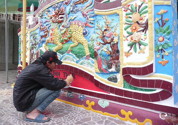 Một người thợ đang hoàn thiện bức bình phong trước đình làng Kế Môn. Ảnh: V.Trọng