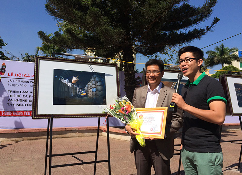 Anh Võ Đình Quýt và tác phẩm “Được mùa” tại triển lãm ảnh ở Đắk Lắk. Ảnh: Văn Thương