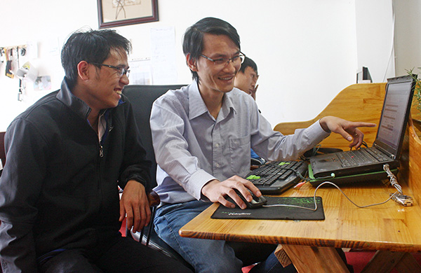 Anh Nguyễn Công Thịnh (phải) trao đổi với kỹ thuật viên khi cập nhật giá cà phê trên sàn giao dịch thế giới. Ảnh: Đ.K