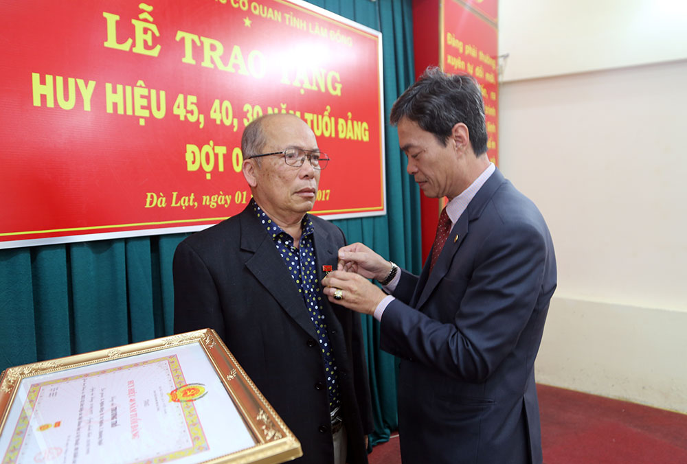 đồng chí Trần Duy Hùng - UVBTV, Trưởng Ban Tổ chức Tỉnh ủy trao huy hiệu 40 năm tuổi đảng cho đảng viên Trương Trổ