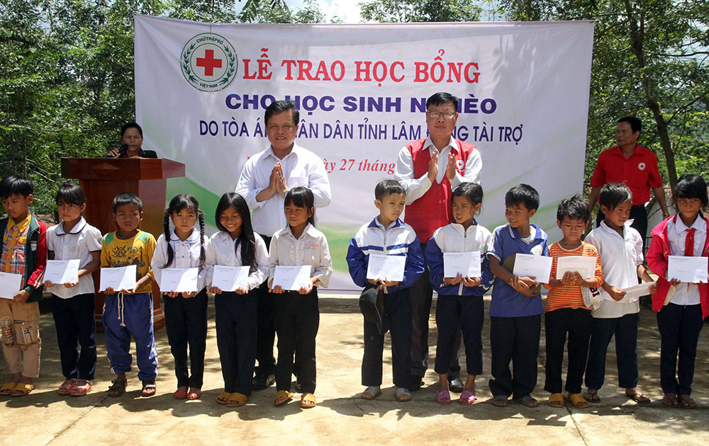 Ông Đào Chiến Thắng, Chánh án Tòa án Nhân dân tỉnh Lâm Đồng (bên trái), và ông Đỗ Hoàng Tuấn, Chủ tịch Hội Chữ thập đỏ Lâm Đồng, trao học bổng cho các em học sinh tại xã Lộc Bắc 