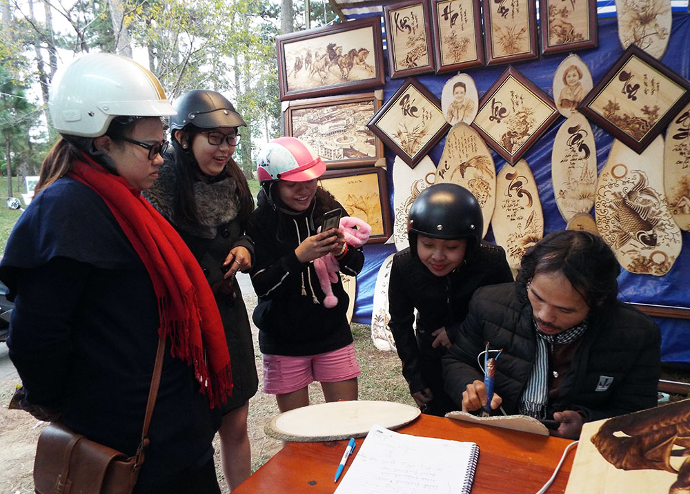 Nghệ nhân tranh bút lửa Khánh Hoàng gây ấn tượng với các du khách trẻ tuổi về nghề truyền thống của Đà Lạt