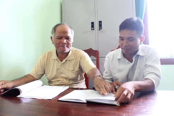 Ông Văn (bên trái) trao đổi công việc với cán bộ địa phương