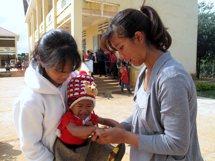Cil KDrim - nhân viên y tế thôn bản Cổng Trời đang kiểm tra, phát hiện một trẻ em bị bệnh tay chân miệng