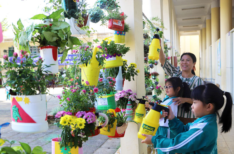 Cô và trò Trường TH Nguyễn Trãi chăm sóc vườn hoa làm từ sản phẩm nhựa tái chế. Ảnh: K.Phúc