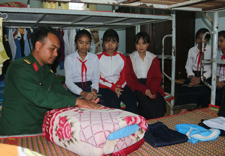 Cán bộ, chiến sĩ Ban CHQS huyện Di Linh hướng dẫn cho học sinh gấp, xếp, chăn, màn, quần áo.