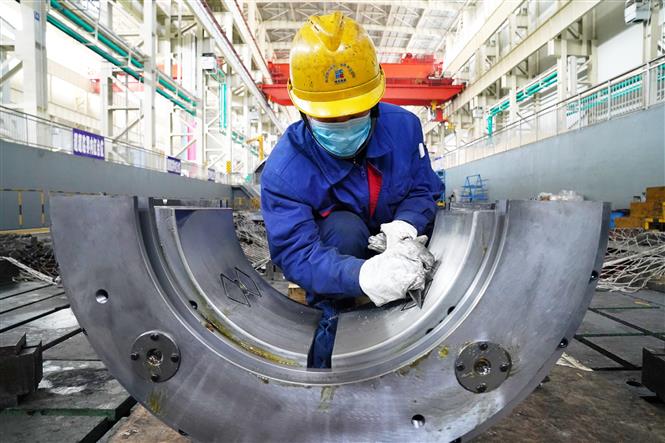 Do ảnh hưởng của dịch COVID-19, sản lượng công nghiệp Trung Quốc giảm lần đầu tiên trong 30 năm. Trong ảnh: Công nhân làm việc trong một nhà máy ở Cáp Nhĩ Tân ngày 9/3