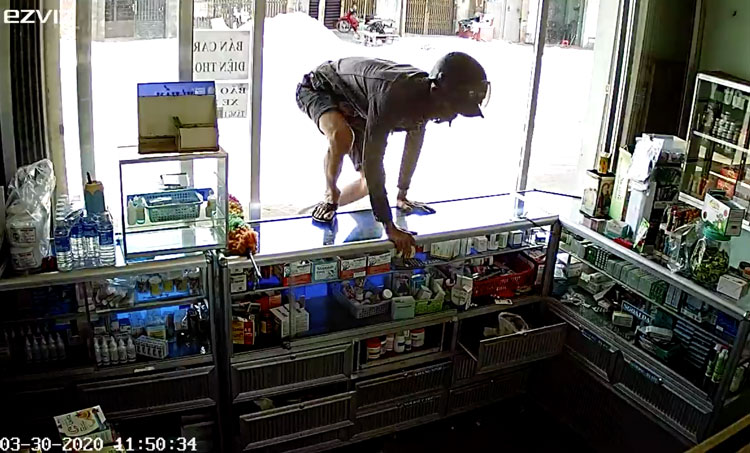 Ảnh chụp từ camera thời điểm đối tượng nhảy qua quầy thuốc trộm đồ khi chủ tiệm đi ra phía sau