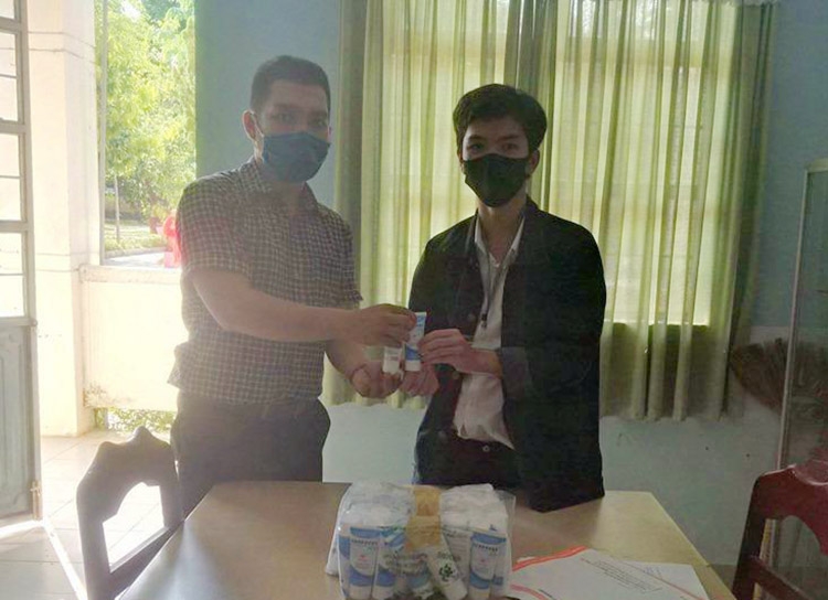 Để tránh tập trung đông người, thầy Lê Viết Hữu (bên trái) trao nước sát khuẩn cho lớp trưởng từng lớp trong sáng 4/5