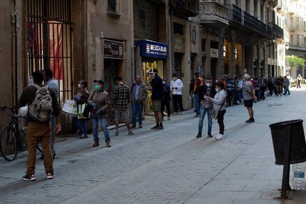 Người dân xếp hàng khi các tình nguyện viên phân phát thực phẩm tại nhà thờ Santa Anna ở Barcelona vào ngày 15/5/2020