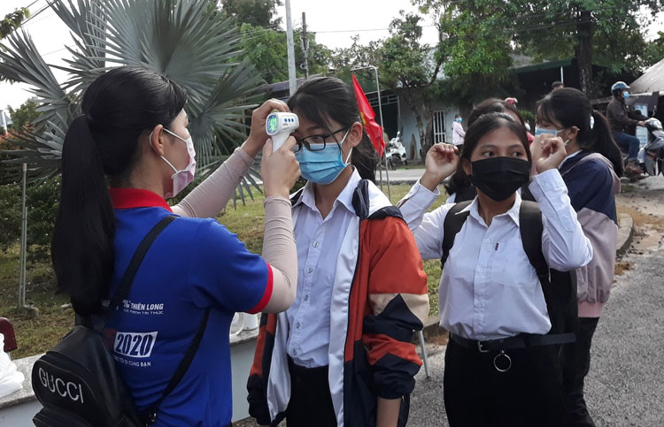 Thí sinh tại huyện Cát Tiên được đội hình thanh niên tình nguyện đo thân nhiệt trước khi vào cổng trường, sau đó tiếp tục được đo thân nhiệt và sát khuẩn tay 1 lần nữa rồi mới vào phòng thi. Ảnh: Ngân Hậu