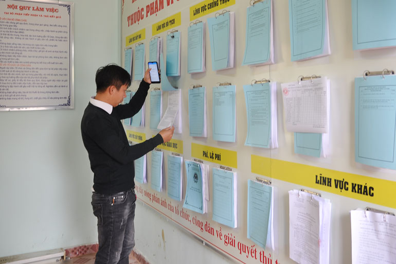 Người dân đang tham khảo bảng niêm yết thủ tục hành chính tại bộ phận một cửa thị trấn Nam Ban - Lâm Hà