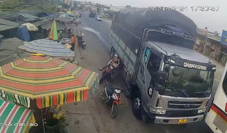 Hiện trường vụ tai nạn khiến 2 người đi xe máy bị xe tải hất văng, thoát chết trong gang tấc (Ảnh chụp màn hình camera an ninh)