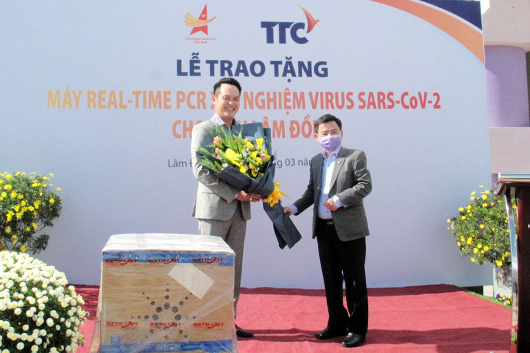 Ông Phan Văn Đa - Phó Chủ tịch UBND tỉnh tặng hoa cảm ơn nhà tài trợ ông Đặng Hồng Anh - Chủ tịch Hội Doanh nhân trẻ Việt Nam, Phó Chủ tịch Tập đoàn TTC trao tặng máy RT- PCR xét nghiệm SARS-COV-2 cho Lâm Đồng