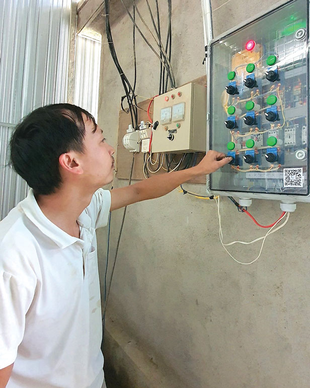 Ông Phí Văn Thìn và bảng điều khiển hệ thống tưới nước, bón phân cho diện tích sản xuất có ứng dụng IoT
