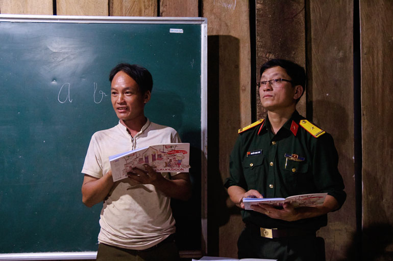 Lớp trưởng Thào Seo Nhà giúp thầy giáo bộ đội điểm danh lớp học ở Tiểu khu 179