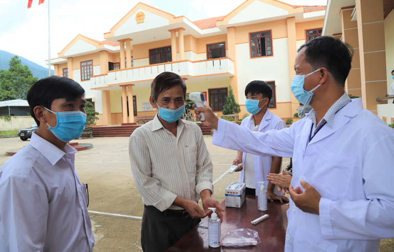 Nhân viên y tế kiểm tra thân nhiệt và sát khuẩn tay cho cử tri tham gia hội nghị tiếp xúc cử tri tại huyện Đạ Huoai
