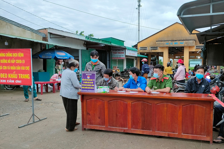 Các lực lượng tại chốt kiểm soát phòng chống Covid-19 tiến hành cấp phát thẻ ra, vào chợ cho người dân tại chợ thị trấn Cát Tiên