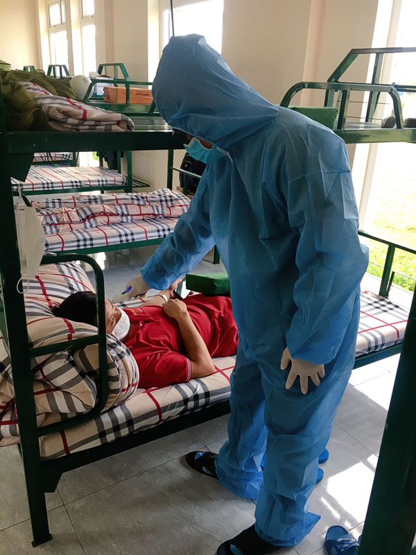 Nhân viên y tế khu cách li Ban Chỉ huy Quân sự huyện Đơn Dương đo thân nhiệt cho người cách ly