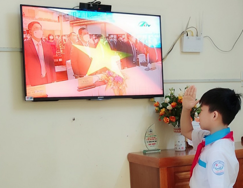 Một học sinh chào cờ qua sóng truyền hình nhân dịp khai giảng năm học mới 2021 – 2022. Ảnh: Khánh Phúc