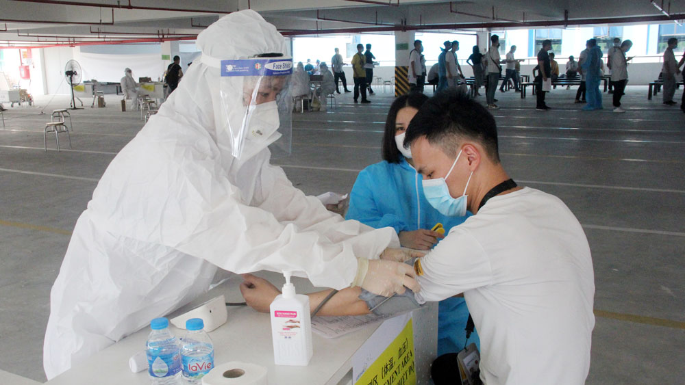 Nhân viên y tế kiểm tra sức khỏe trước khi tiêm vaccine phòng COVID-19 cho người lao động tại Bắc Giang