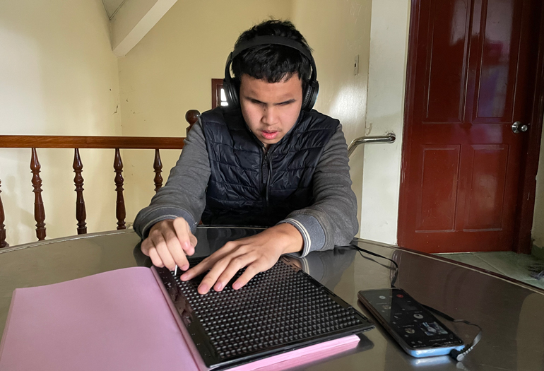 Em Nguyễn Văn Hoàng – học sinh hòa nhập cộng đồng, lớp 10A15, Trường THPT Trần Phú học trực tuyến bên bảng chữ nổi