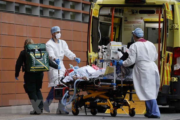 Nhân viên y tế chuyển bệnh nhân nhiễm COVID-19 tới bệnh viện ở London, Anh.
