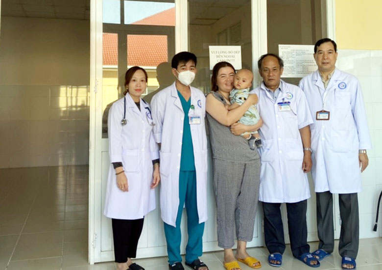 Bệnh nhi đã được điều trị sốt xuất huyết thành công được mẹ bế chụp hình lưu niệm với các y bác sĩ, lãnh đạo Bệnh viện Nhi Lâm Đồng