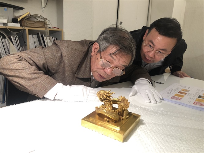 Tiến sĩ Phạm Quốc Quân và tiến sĩ Nguyễn Văn Đoàn nghiên cứu, đánh giá hiện trạng của ấn vàng ngay tại văn phòng hãng đấu giá Millon