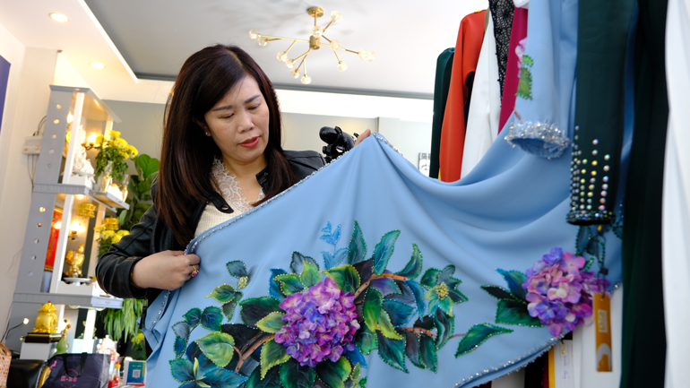 Nghệ nhân Huỳnh Hoàng Vân chăm chút từng cánh hoa đất sét để đưa lên tà áo dài