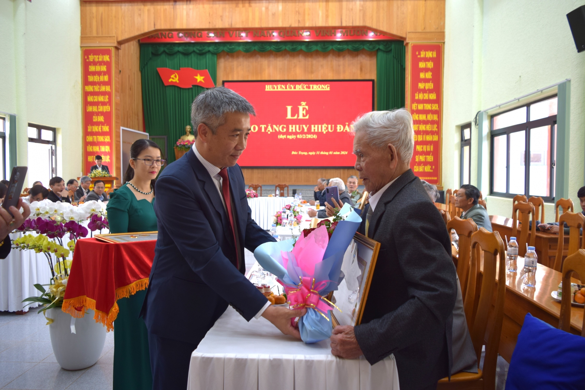 Đồng chí Bùi Sơn Điền - Bí thư Huyện ủy, trao huy hiệu 65 năm tuổi Đảng cho đảng viên Bùi Quang Dục (Đảng bộ xã Tân Hội)