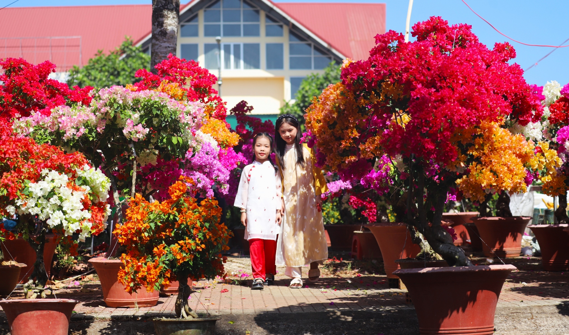Hai chị em tạo dáng để bố mẹ chụp hình ghi lại khoảnh khắc tràn ngập sắc xuân tại chợ hoa xuân